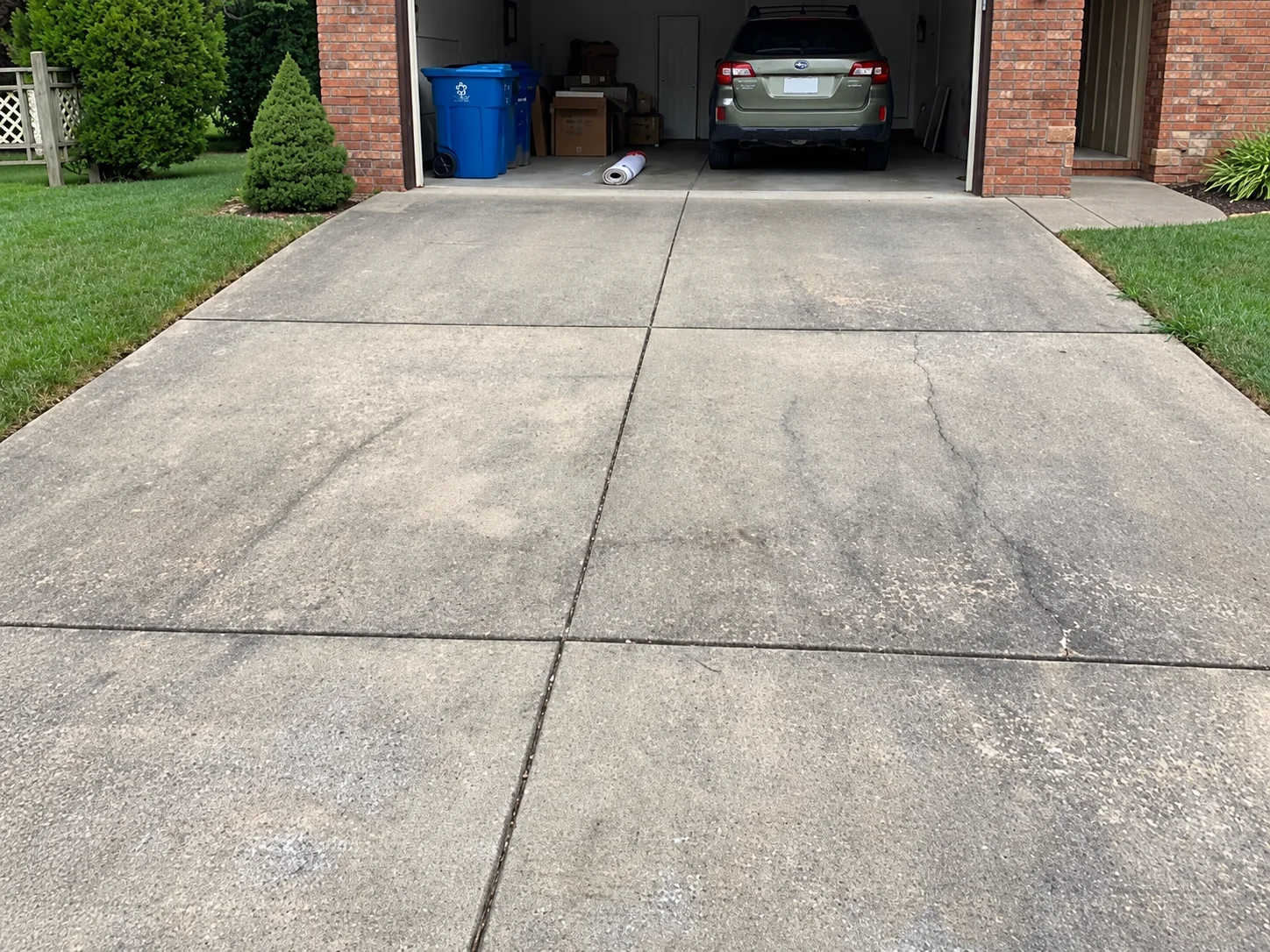 Residential concrete driveway with dark organic staining and surface buildup